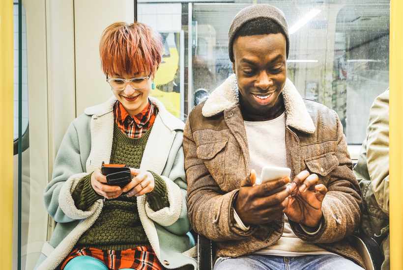 Multiracial Hipster Friends Couple Having Fun With Smartphone In Subway Train Urban
