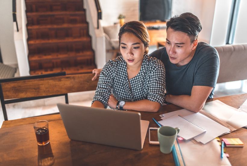 Serious Couple Using Laptop While Sitting At Home 