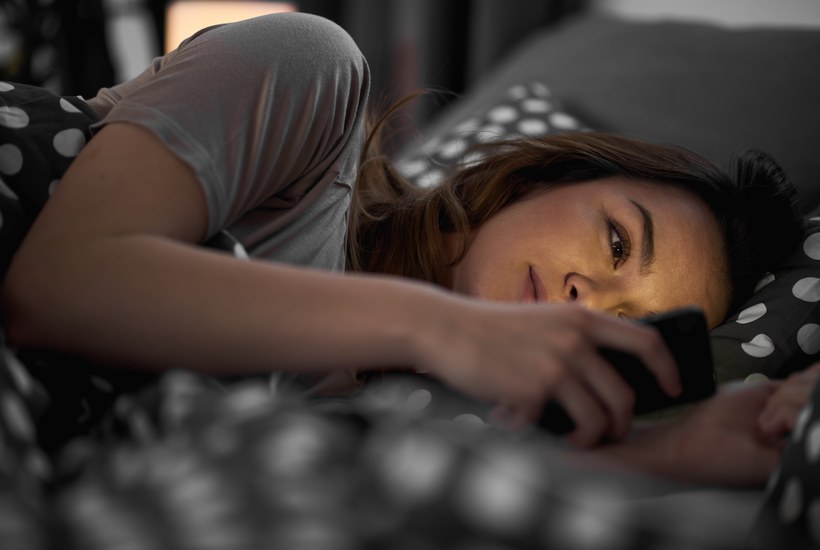 Girl Using Smart Phone And Lying Down In Bed 